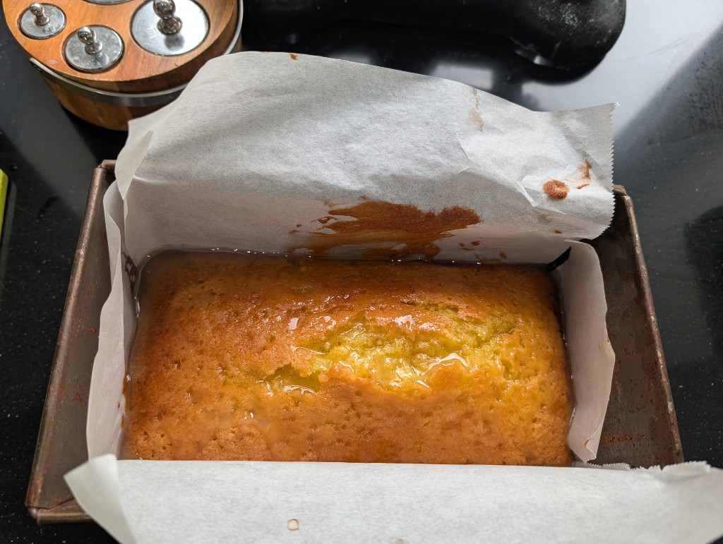 Drizzle poured over the warm cake in the tin